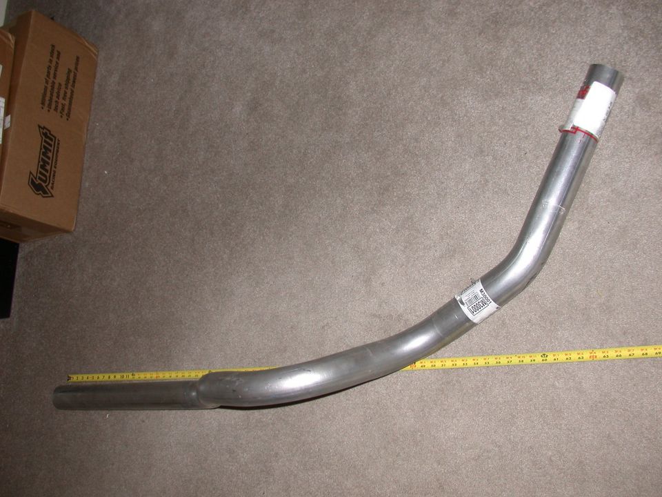 Curved stainless exhaust pipe on carpet next to a yellow tape measure