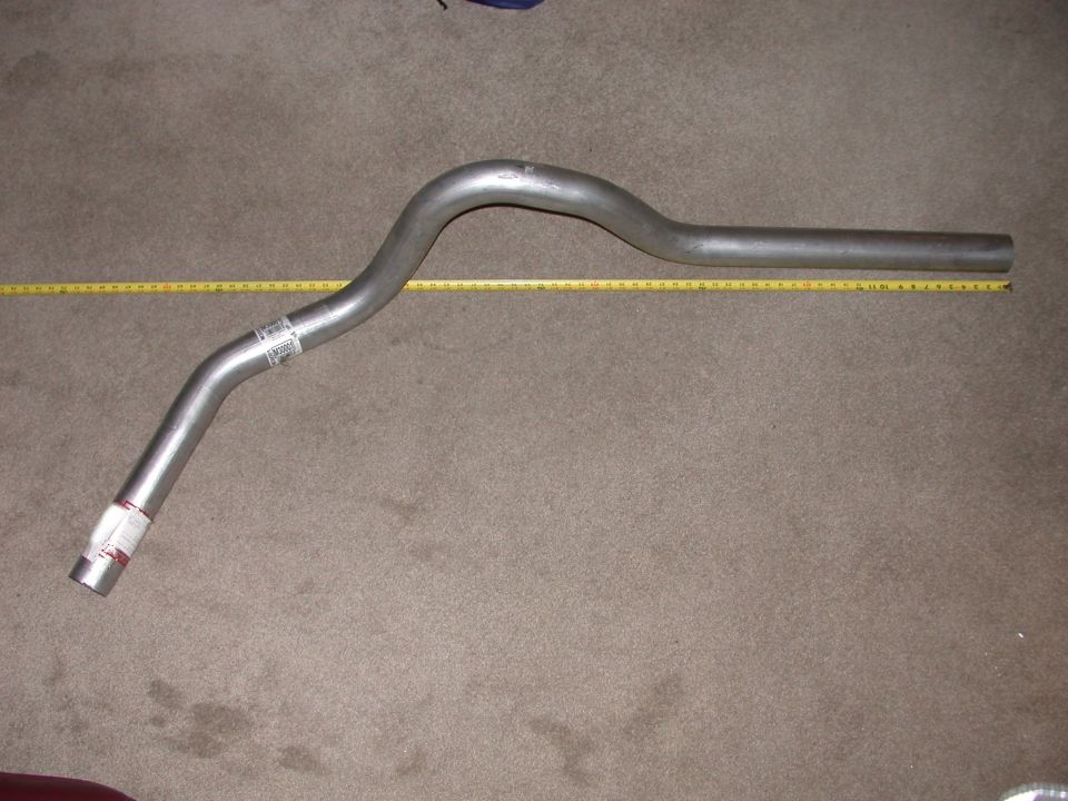 Bent stainless exhaust pipe on carpet next to yellow tape measure