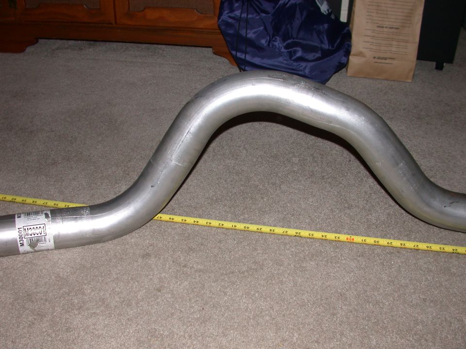 Bent stainless exhaust pipe on carpet with tape measure and M30001 label