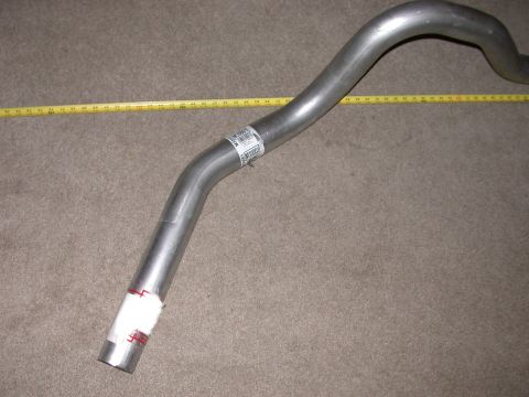 1995 Ford Bronco - A metal exhaust pipe lies on a carpeted surface next to a yellow measuring tape.