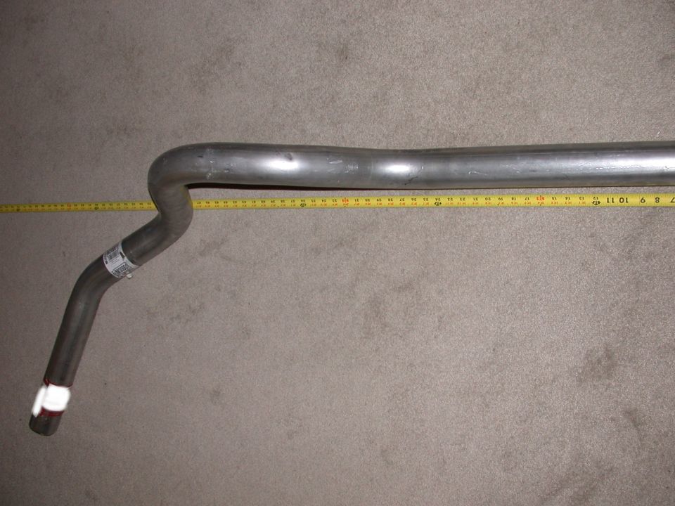 Unpainted bent exhaust pipe on carpet with yellow tape measure alongside