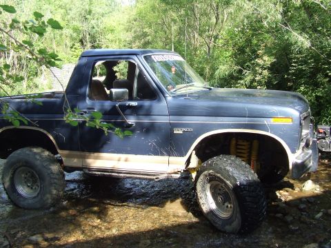 1986 Ford Bronco - This 1986 Ford Bronco is navigating a rocky stream, its tires kicking up water.