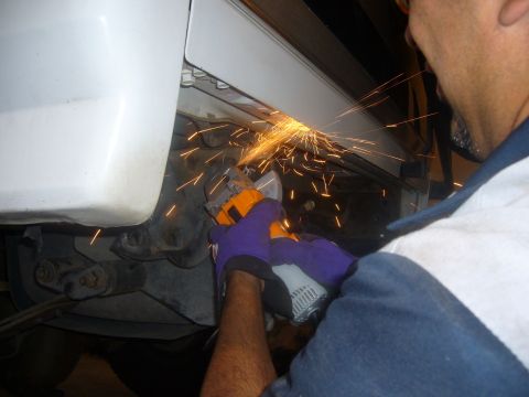 1992 Ford Bronco - A person uses an angle grinder on the underside of a vehicle, creating a shower of sparks.