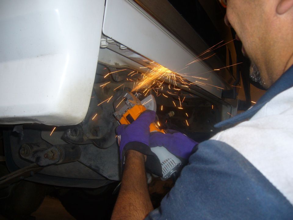 person grinding on vehicle frame with sparks flying