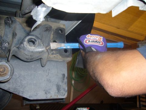 1992 Ford Bronco - A mechanic uses a pry bar on a vehicle's suspension system, wearing a branded glove.