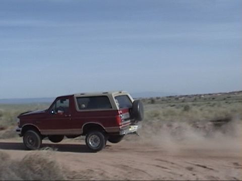 1994 Ford Bronco - This 1994 Ford Bronco is captured mid-air, kicking up dust on a dirt road.