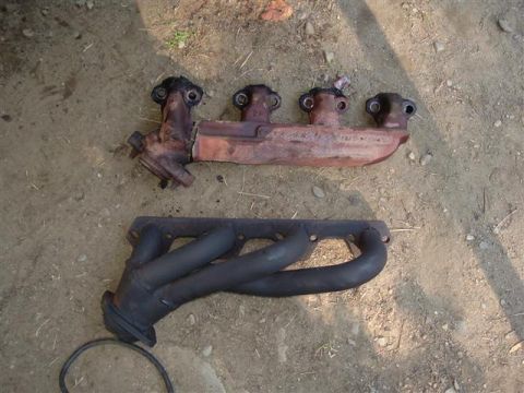 1991 Ford Bronco - Two exhaust manifolds are shown on the ground, one appears to be a replacement part.
