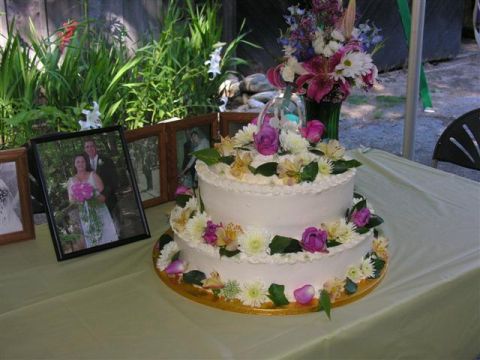 1966 Land Rover Discovery - A two-tiered wedding cake is decorated with flowers and sits next to framed photographs of a couple.
