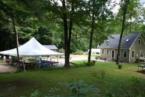 1966 Land Rover Discovery - Outdoor party setup with a tent, tables, balloons, and a house in a wooded area.