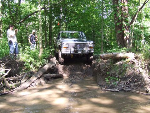 1986 Ford Bronco - 1986 Ford Bronco navigates a challenging off-road course in a forest.