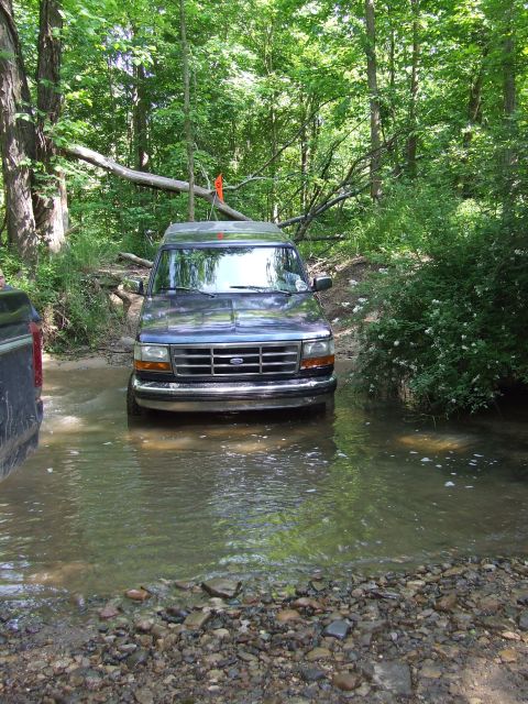 1986 Ford Bronco - Ford Bronco navigates a water crossing on a wooded trail.