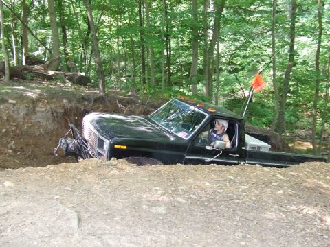 1986 Ford Bronco - Pickup truck navigating a challenging off-road terrain, stuck in a deep ditch.