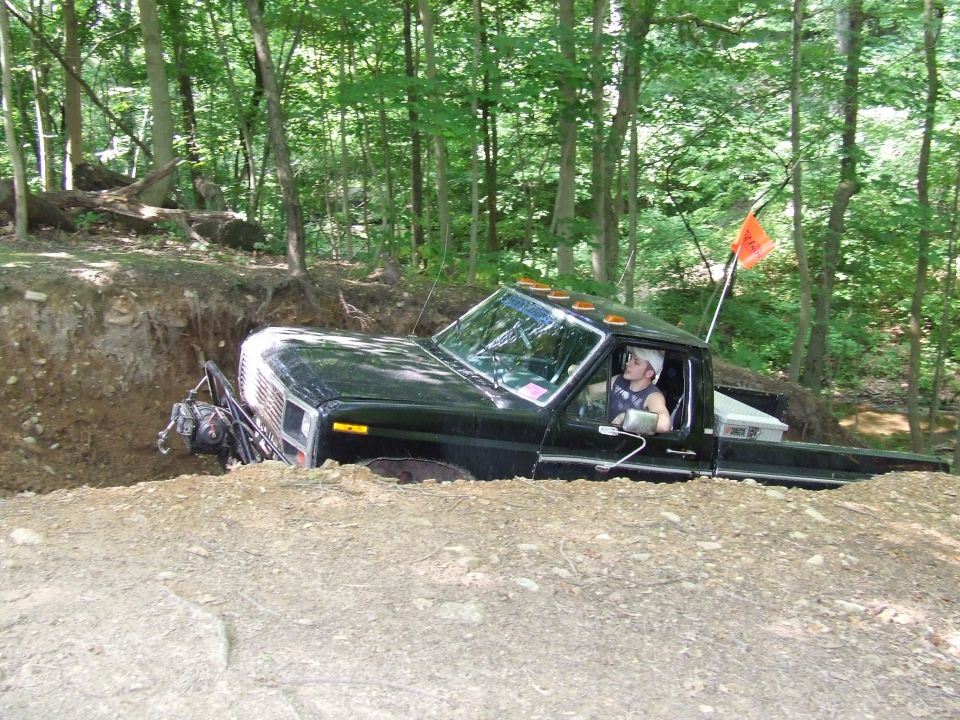 Black pickup truck with orange flag stuck in a dirt ditch off-road