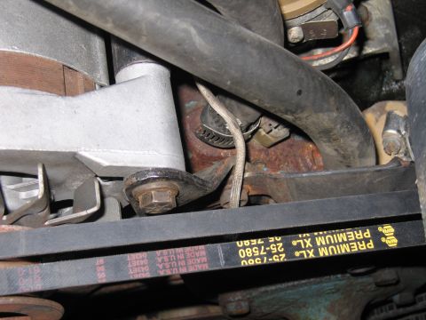 1991 Ford LTD Crown Victoria - Close-up of a Premium XL 25-7580 Made in USA V-belt running past brackets, bolts, and hoses in an engine bay.