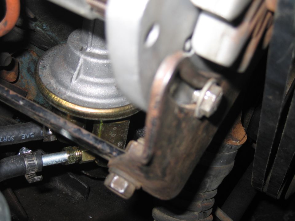 Close-up of an engine pulley, bracket, and bolted bracket inside an engine bay