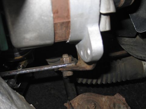 1991 Ford LTD Crown Victoria - Close-up of an alternator with its mounting bracket and adjustment arm bolted in place inside an engine bay.