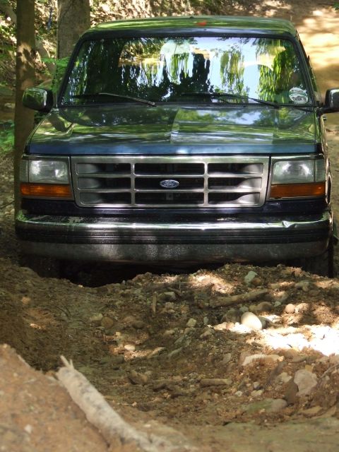 1986 Ford Bronco - Front view of a blue Ford Bronco navigating a dirt path.