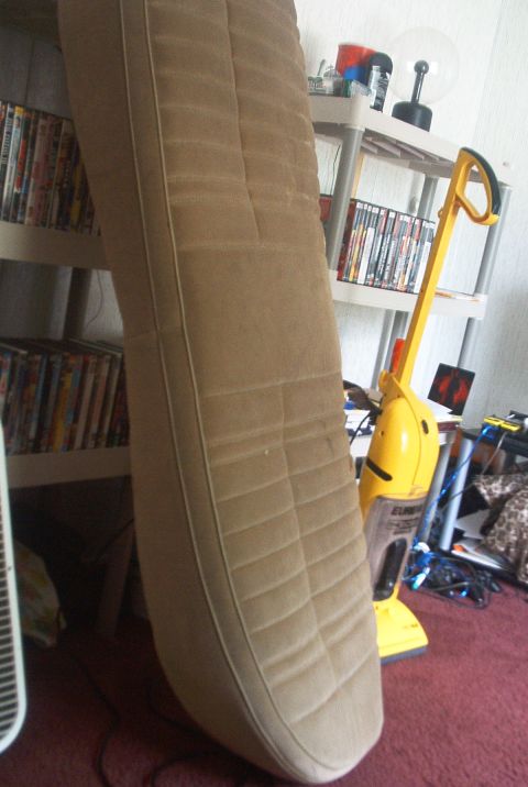 1985 Ford Crown Victoria LTD - A tan seat cushion with horizontal stitching is shown in a room with shelves and a vacuum cleaner.