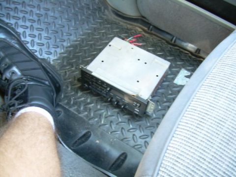 1988 Ford Bronco - Car stereo head unit removed from its dash, resting on the floor.