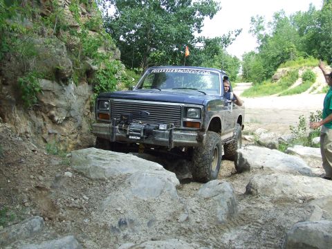 1986 Ford Bronco - This Ford Bronco is tackling a challenging off-road course with large rocks and steep inclines.