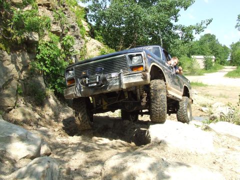 1986 Ford Bronco - This lifted SUV navigates a rocky incline, its off-road capabilities.