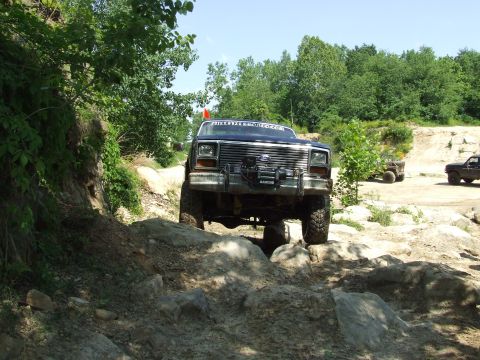 1986 Ford Bronco - Off-road truck navigates a challenging rocky course with other vehicles present.