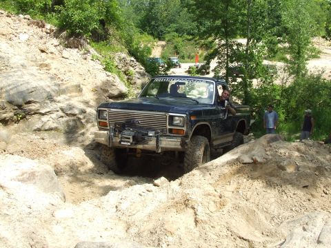 1986 Ford Bronco - Ford F-Series truck tackling a challenging off-road course with spectators watching.