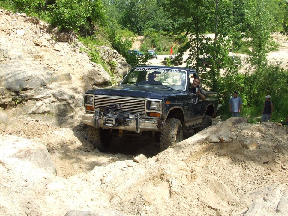 Dark blue Ford F-Series truck navigating a rocky off-road trail. A winch is mounted on the front bumper