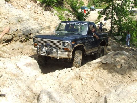 1986 Ford Bronco - This Ford F-Series truck navigates a challenging off-road obstacle course with other vehicles in the background.