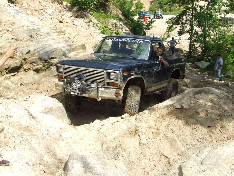 Ford F-Series truck going over rocks on a trail. A person is in the driver's seat