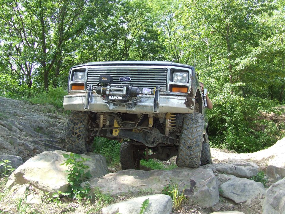 1986 Ford Bronco navigating rocks on an off-road trail, front view