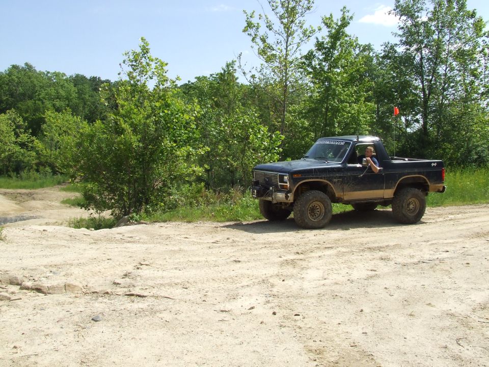Dark blue pickup truck with off-road tires and suspension, driving on a dirt road