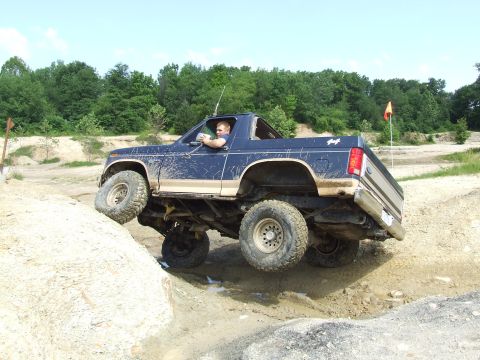 1986 Ford Bronco - Driver maneuvers a 1986 Ford Bronco through a muddy, rocky off-road trail.