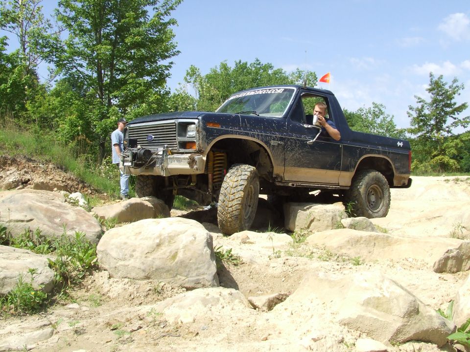 Dark blue Ford Bronco navigating a rocky trail with a driver inside