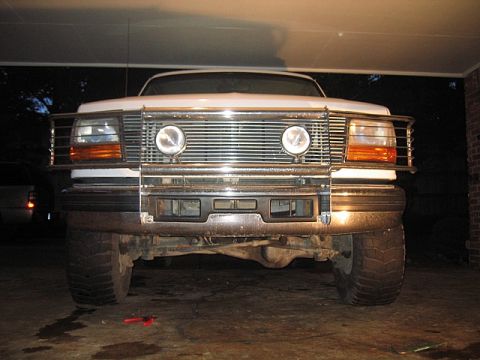1996 Ford Bronco - The front of a white SUV is shown, a large chrome grille guard and prominent headlights.