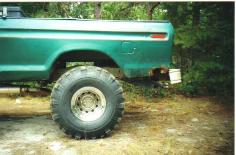 1979 Ford F-250 - Rear view of a 1979 Ford F-250 pickup truck with a large tire and visible rust.