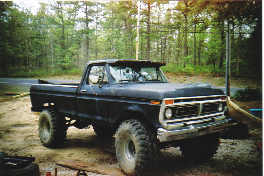 Black Ford F-250 truck with large tires, parked outdoors. Front 3/4 view