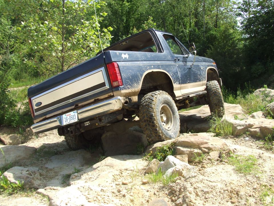 1986 Ford Bronco climbing over rocks on a trail. License plate 16-0583