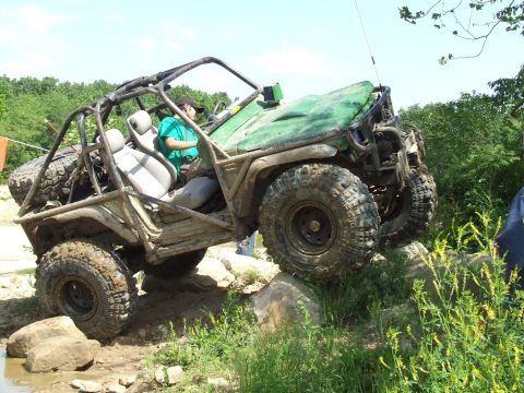 1986 Ford Bronco - Modified off-road vehicle tackles a rocky trail with a driver inside.
