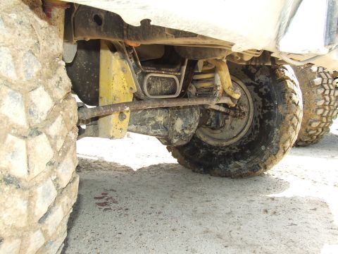 1986 Ford Bronco - Close-up view of the undercarriage, suspension, and large tires of a vehicle.