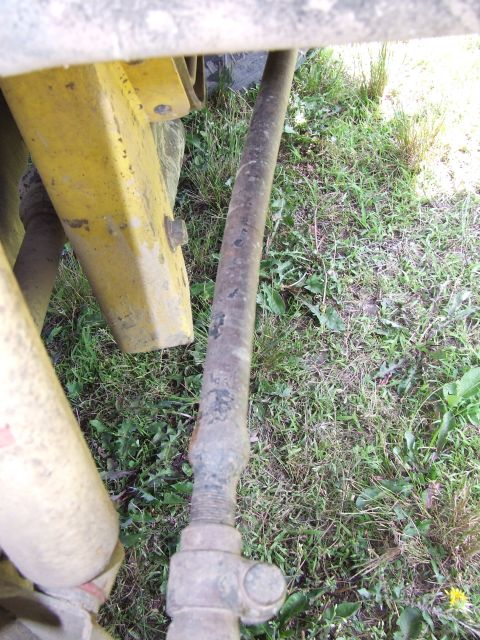 1986 Ford Bronco - A close-up view of a vehicle's suspension system, showing a rusty metal rod and part of the yellow frame.