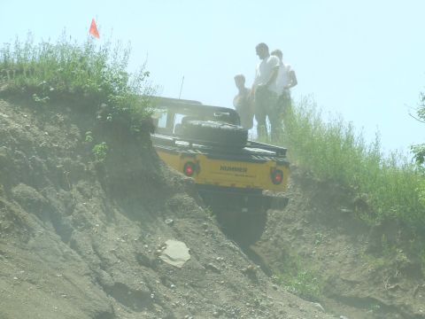 1986 Ford Bronco - Hummer navigates a challenging off-road course with spectators observing the action.