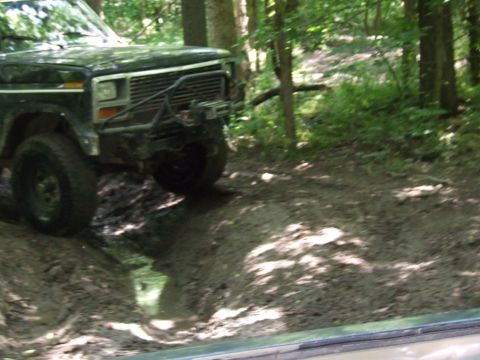 1986 Ford Bronco - This SUV is navigating a muddy path through a forest.