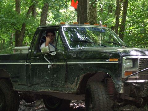 1986 Ford Bronco - A man gives a thumbs up from the driver's seat of a black pickup truck off-road.
