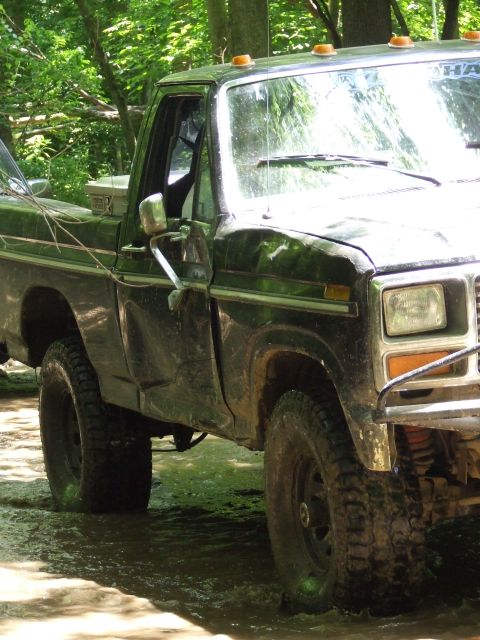 1986 Ford Bronco - This pickup truck, likely from the late 1970s, navigates a muddy, wooded area.