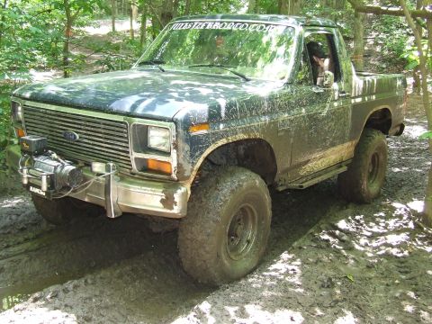 1986 Ford Bronco - Mud-covered Ford Bronco navigates a challenging off-road course.