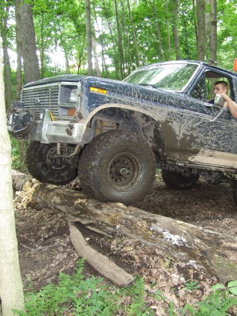1986 Ford Bronco - This 1986 Ford Bronco navigates a challenging off-road course, its tires caked in mud from the trail.