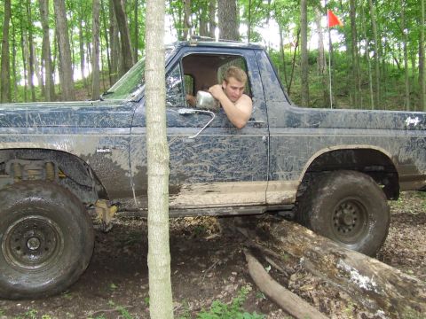 1986 Ford Bronco - A 1986 Ford Bronco navigates a challenging off-road course in a wooded area.