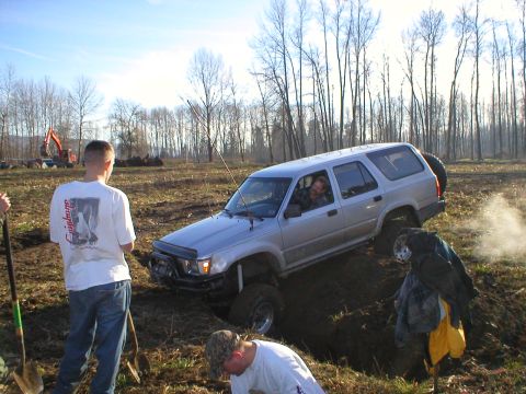 1978 Ford Bronco - A silver SUV navigates a muddy off-road course with a driver visible.