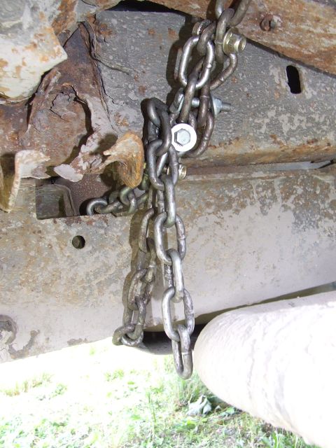 1986 Ford Bronco - Close-up of a heavily rusted vehicle frame with chains attached.